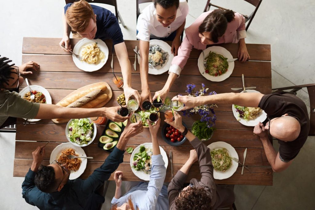 Friends are cheering over a dring during a meal. The table is filled with great food.