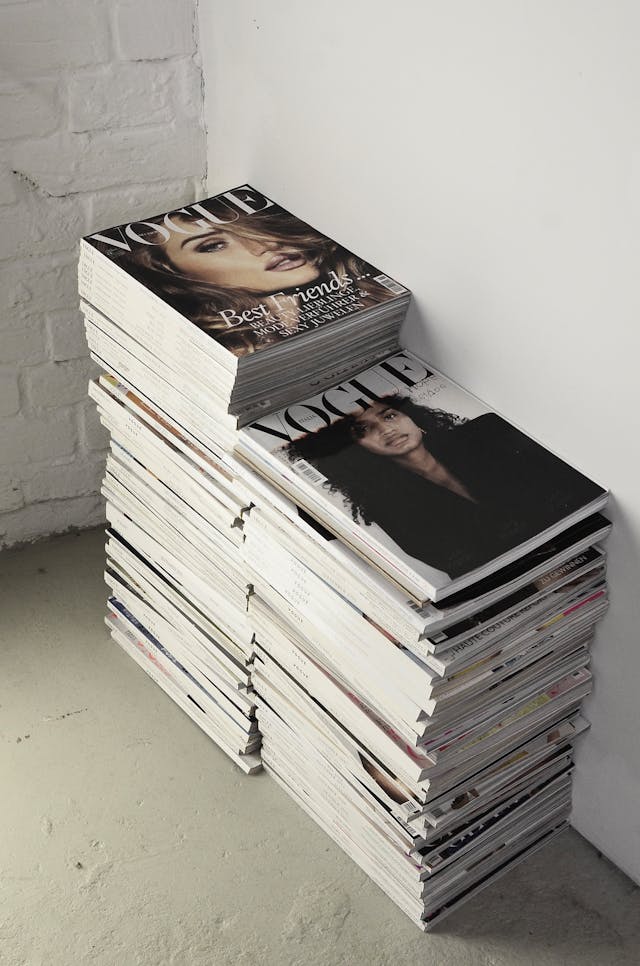 A staple or collection of numerous Vogue magazines on the ground.