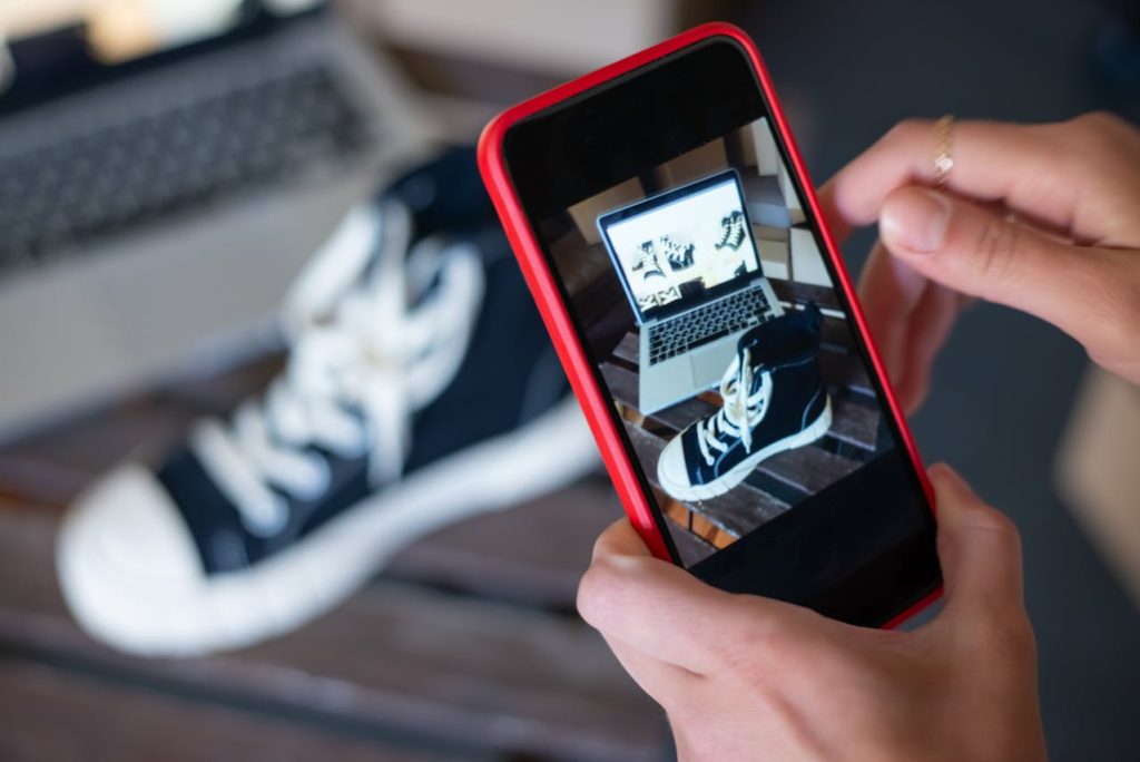 Someone taking a photo of a shoe in front of a laptop