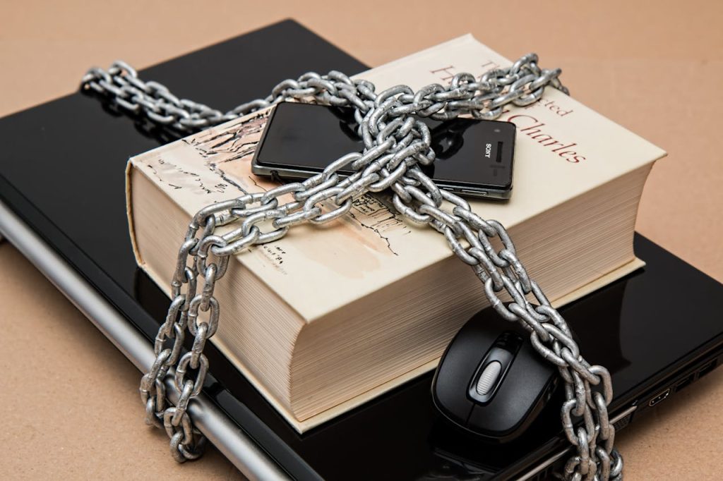 A computer, a book, a phone and a mouse chained like a present